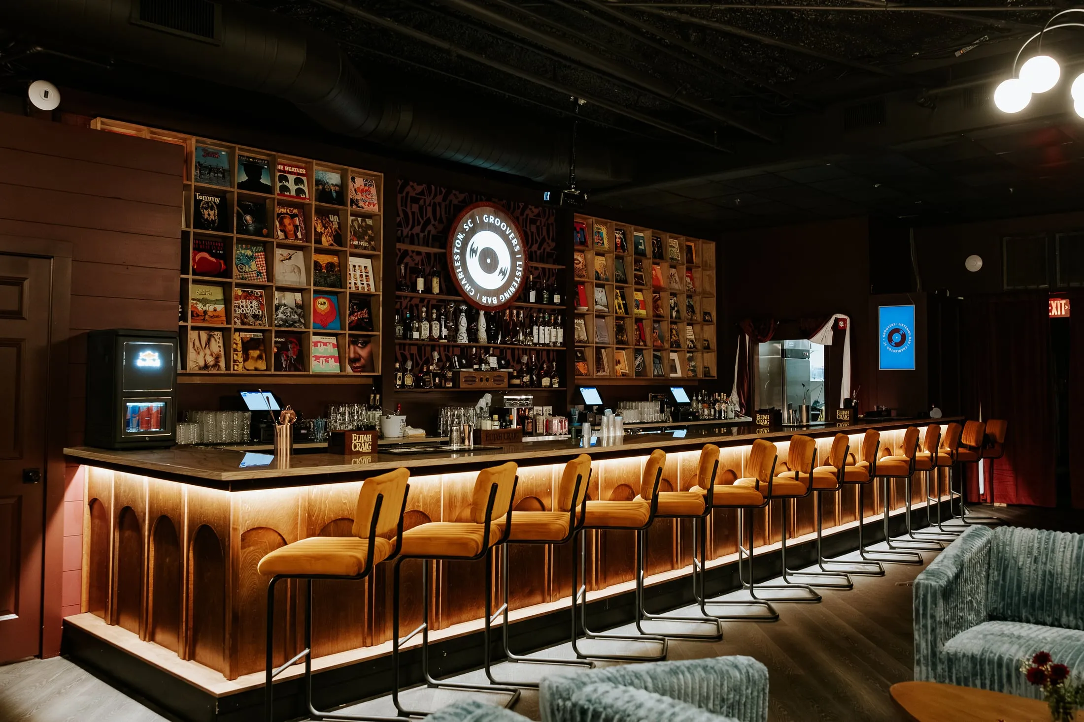 The full length of the bar front at Groovers, lit from underneath, with the record display wall beyond.