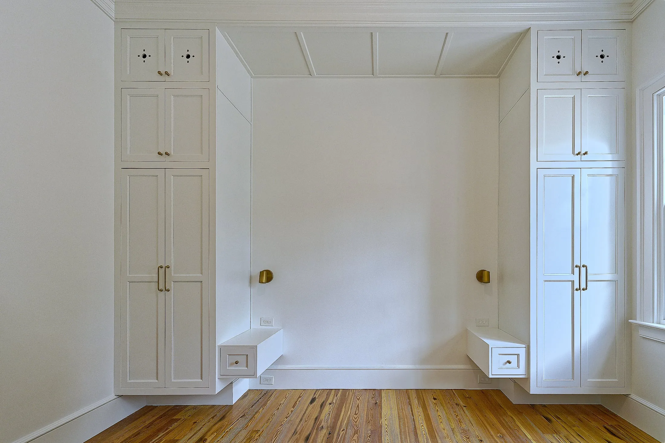 Guest bedroom wall with matching built-in armoires flanking the bed space and floating bedside drawers.
