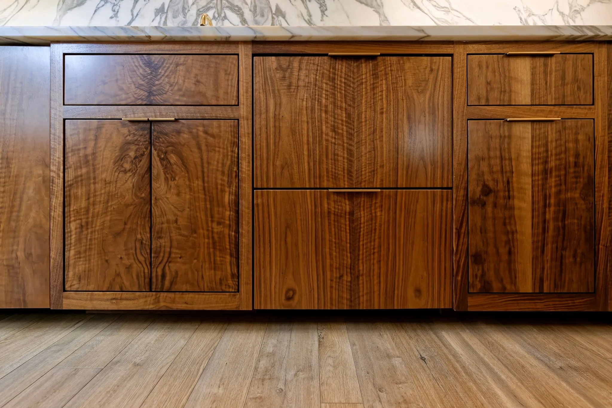 Bar base cabinets in figured, book-matched walnut with slim brass pulls.