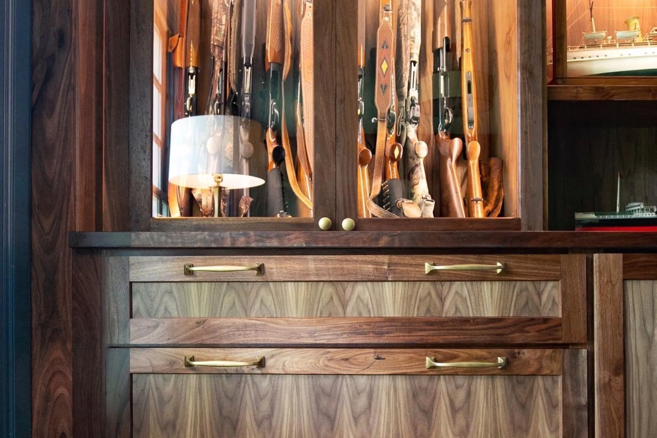 A wooden display case filled with vintage rifles and shotguns.