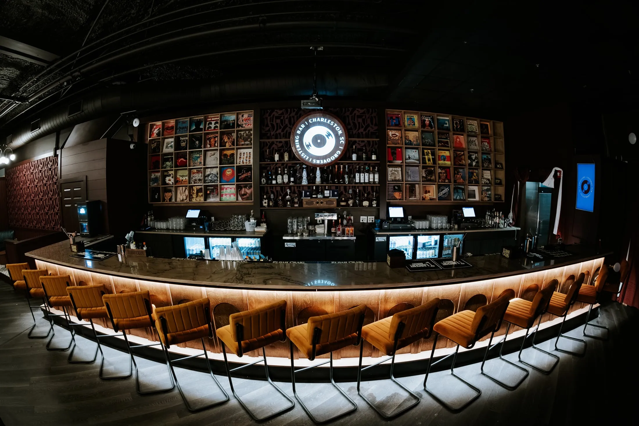 The curved bar front at Groovers, lit along its base, with the record display wall behind.