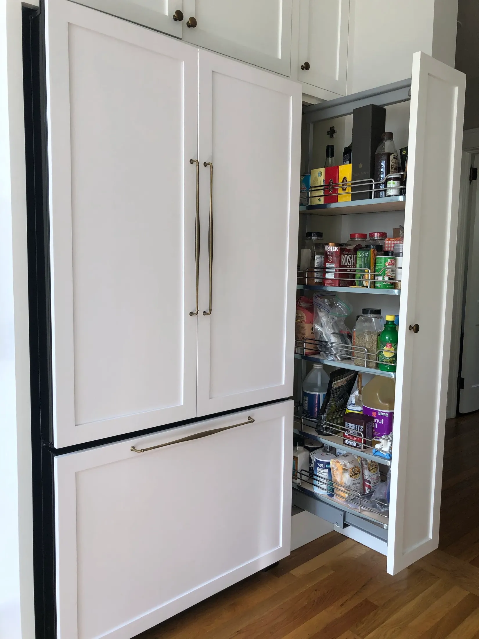 Open kitchen cabinet with various food and beverage items on metal shelves.
