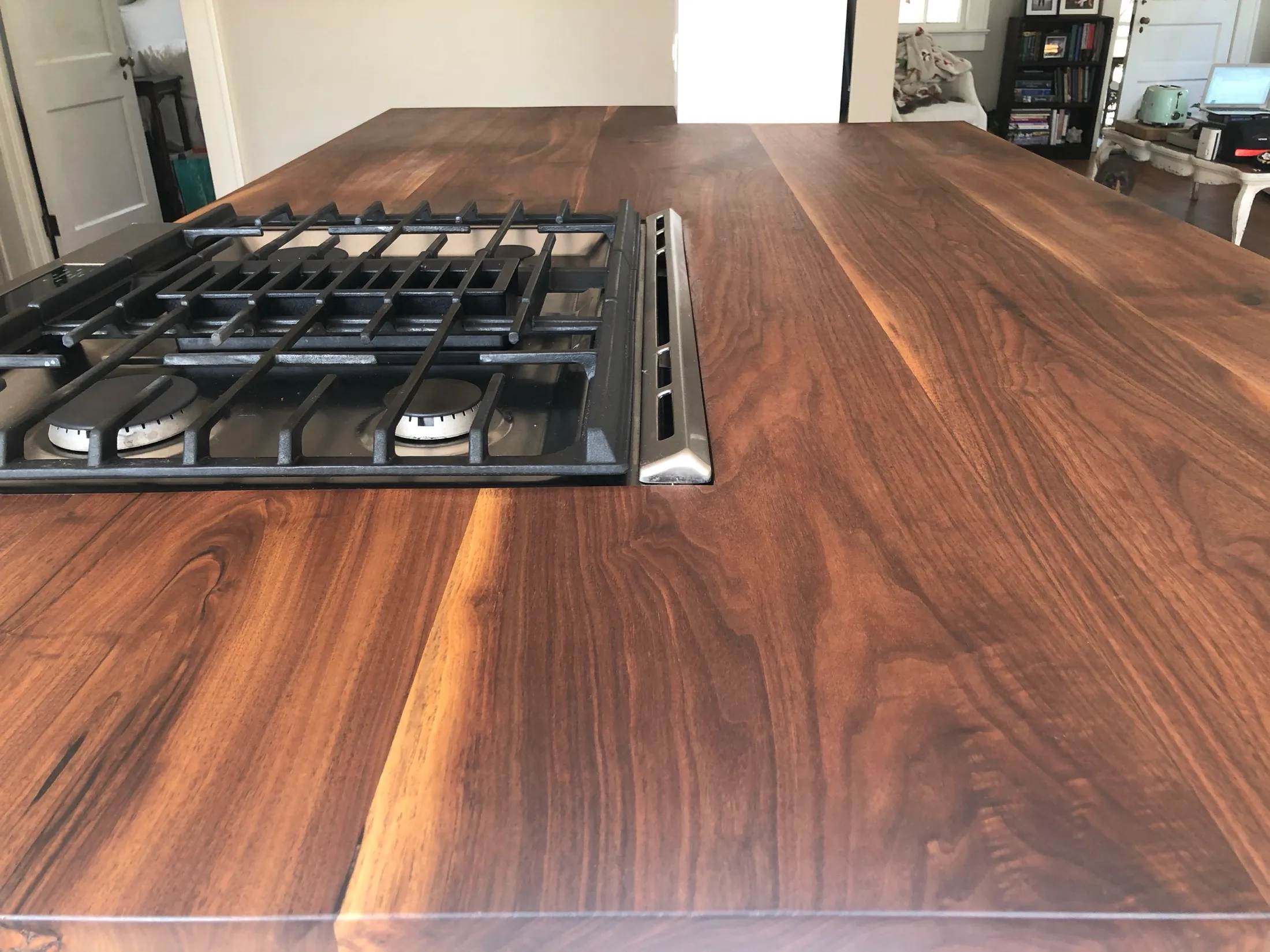Close-up of a wooden kitchen countertop with a built-in gas stove with four burners.