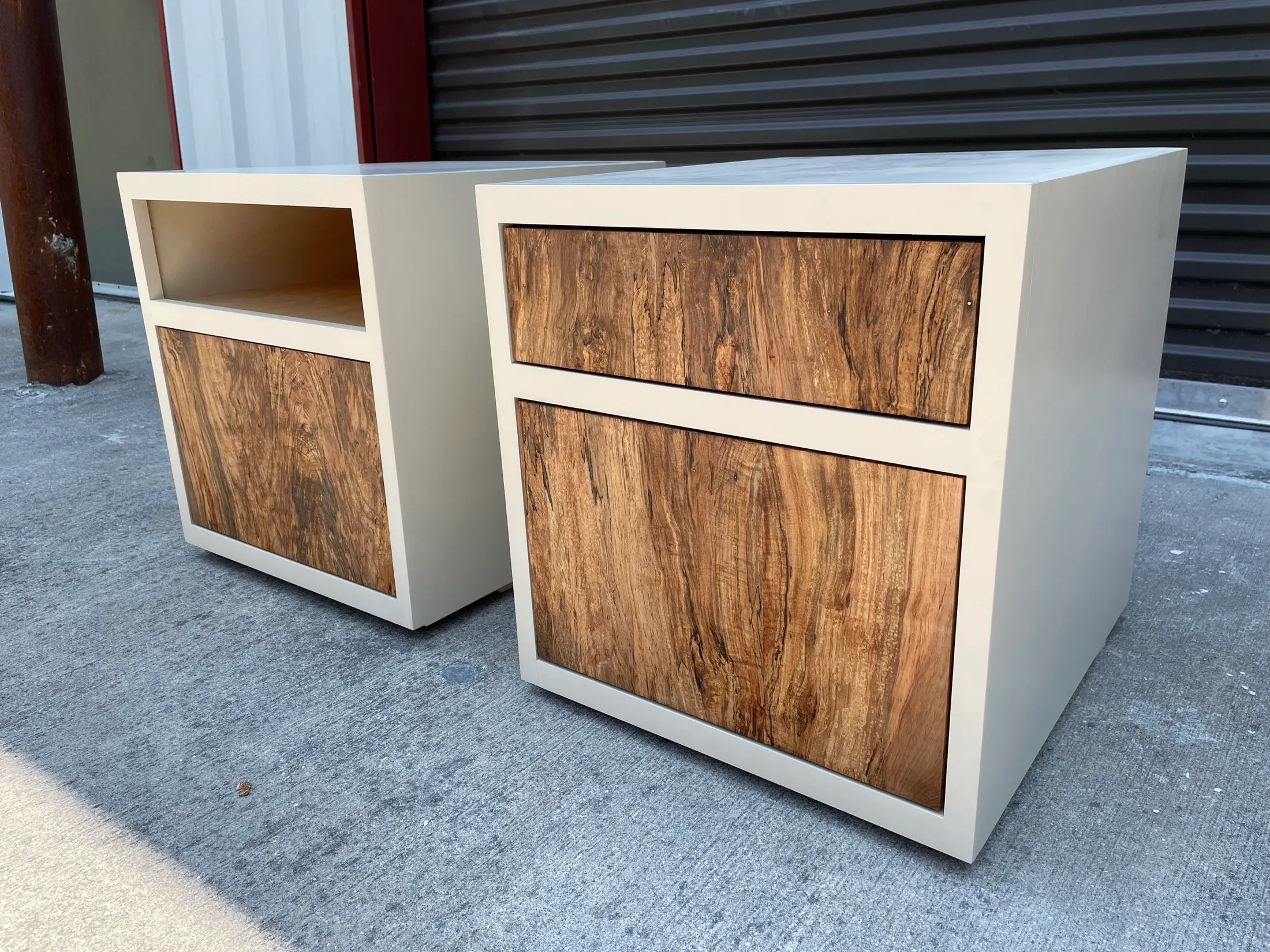 Pair of modern white cabinets with natural wood panel accents, placed outdoors on concrete ground.