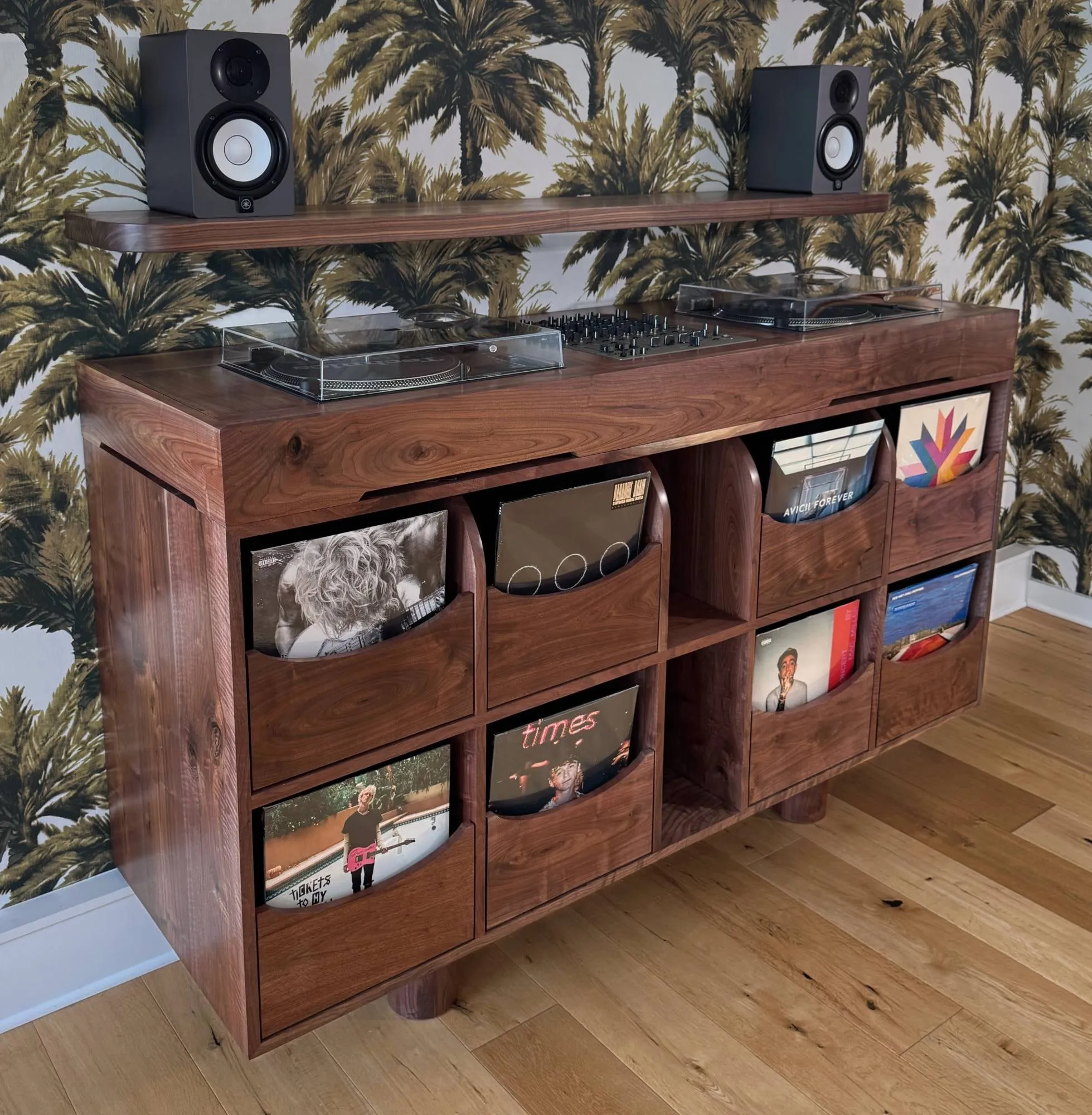 Solid walnut record console with two turntables and a mixer on top, record bins with curved fronts, and a matching walnut speaker shelf.