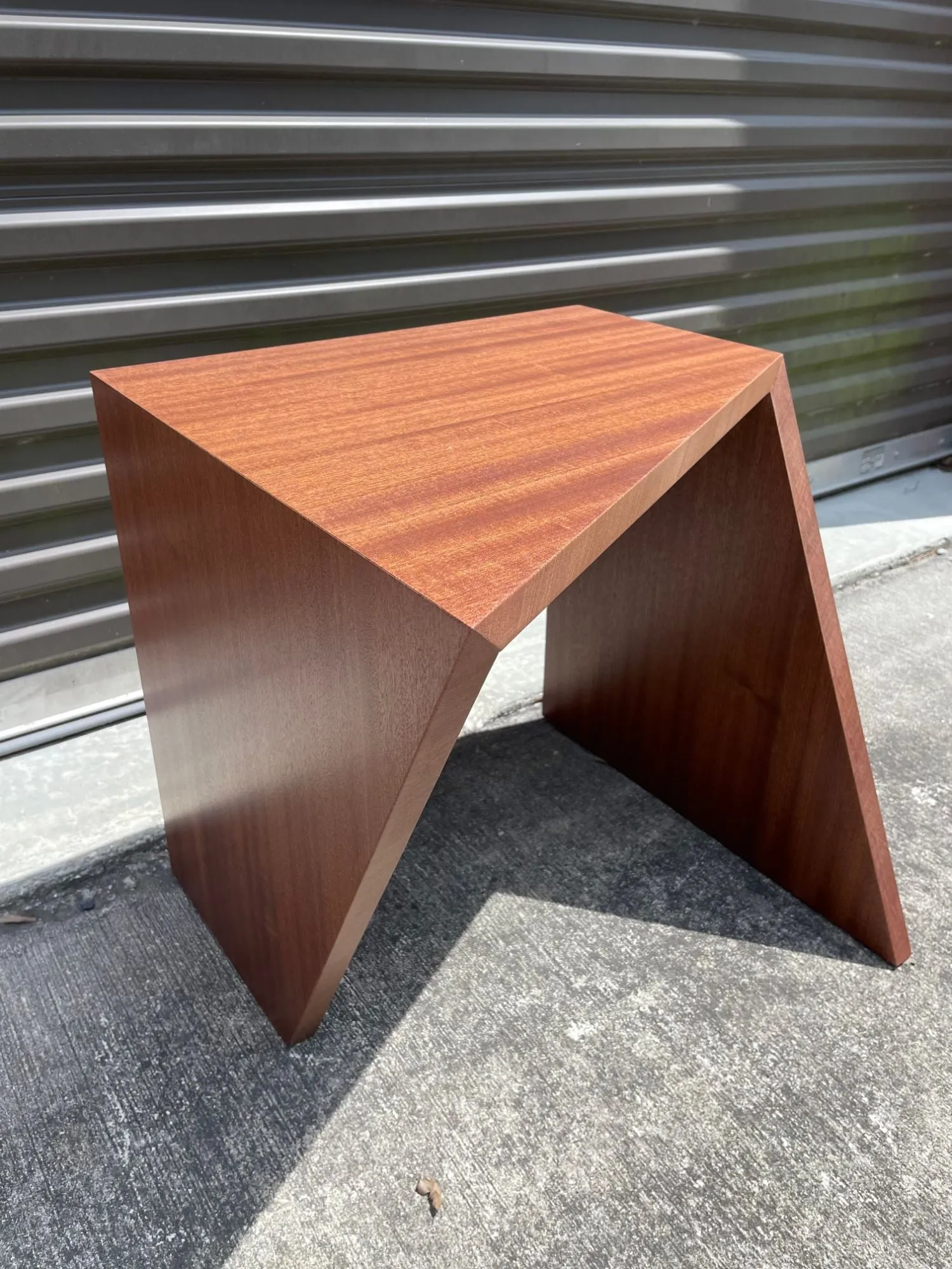 Sapele geometric side table from above, showing the ribbon-striped grain.