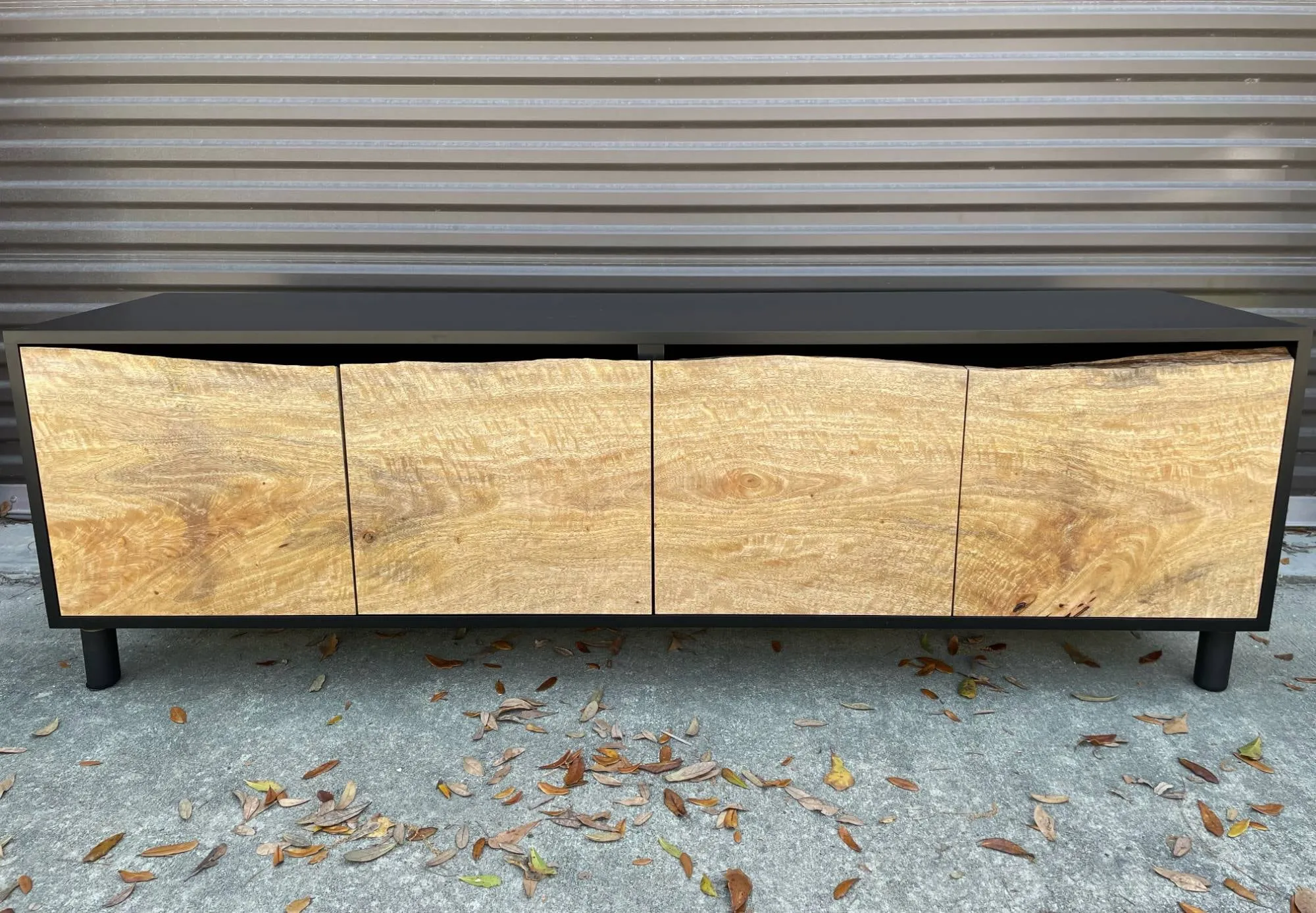 Black credenza with four live-edge mango wood doors on black legs, front view.